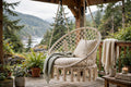 Natural macramé hanging chair in knotted cream cotton hanging on a porch