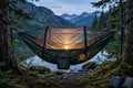 Pro camping hammock with built-in bug net at a lakeside campsite at dusk